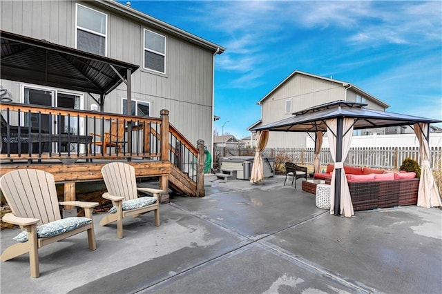 view of patio / terrace featuring a hot tub, a fenced backyard, a gazebo, a wooden deck, and outdoor lounge area