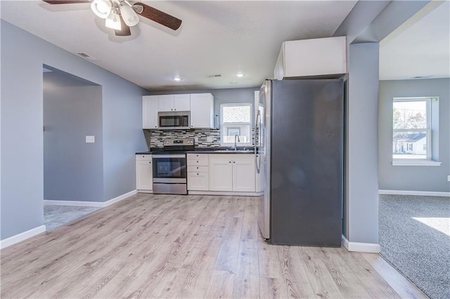 kitchen featuring sink, white cabinetry, stainless steel appliances, decorative backsplash, and light wood-type flooring