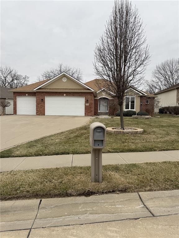 ranch-style house with a front yard, brick siding, driveway, and an attached garage