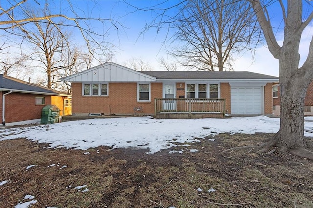 snow covered back of property featuring a garage