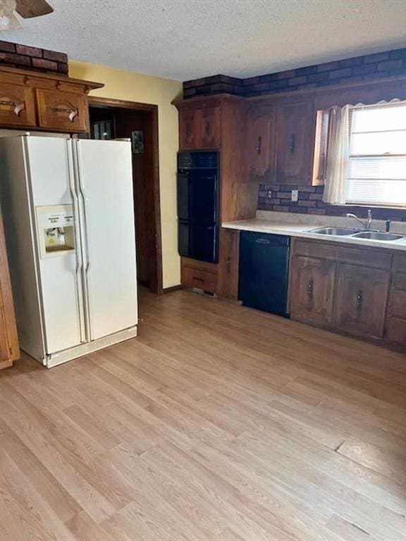 kitchen with sink, black appliances, light hardwood / wood-style flooring, a textured ceiling, and backsplash