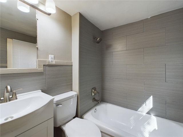 full bathroom featuring tile walls, backsplash, tiled shower / bath combo, vanity, and toilet