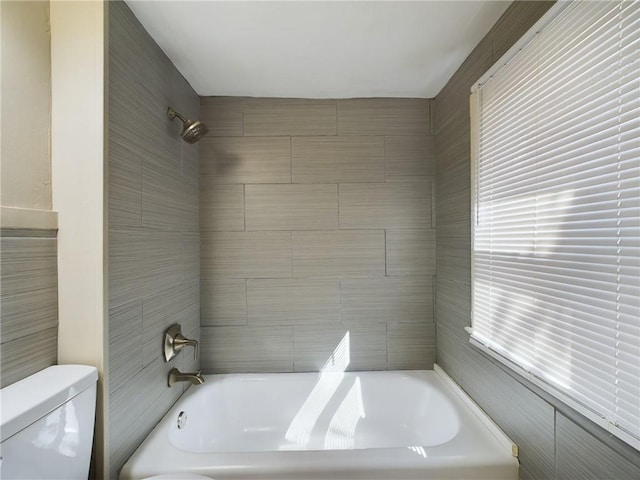 bathroom with toilet and tiled shower / bath