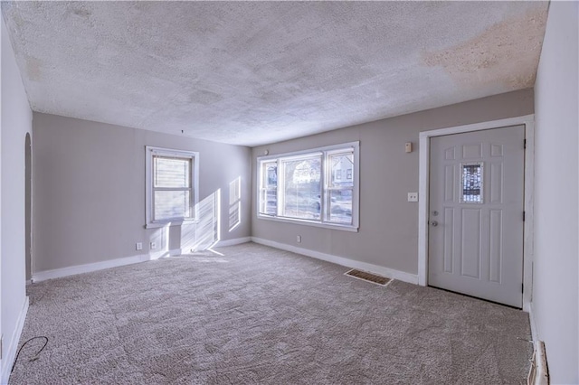 carpeted entryway with a textured ceiling