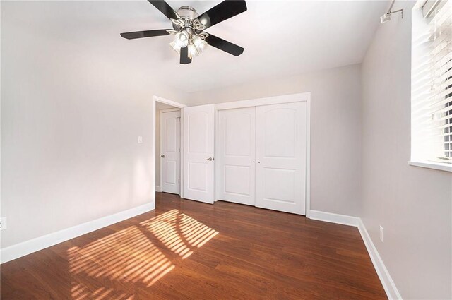 unfurnished bedroom with dark wood-type flooring, ceiling fan, and a closet