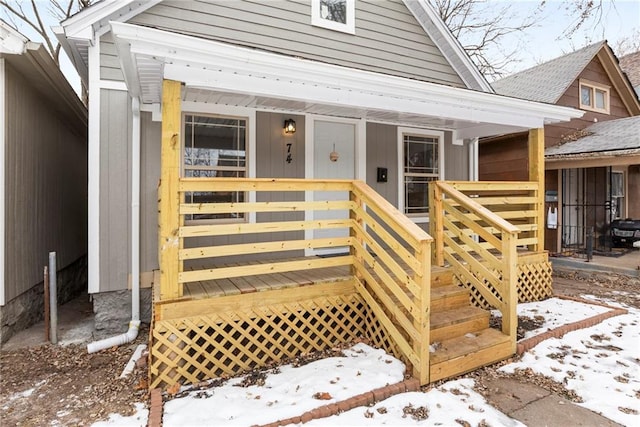 snow covered property entrance with a porch