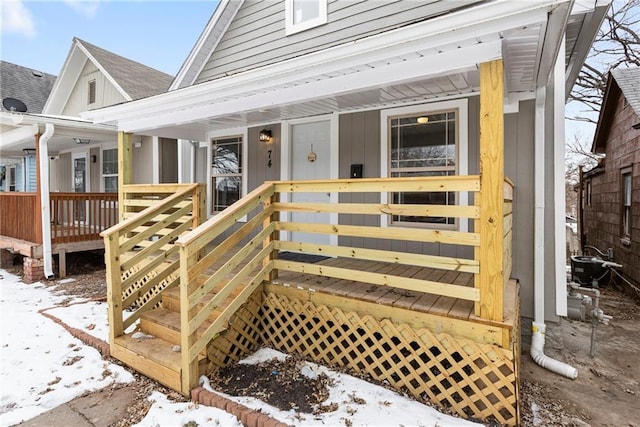 snow covered property entrance with cooling unit and covered porch