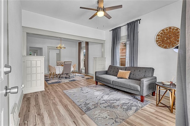 living room with hardwood / wood-style flooring and ceiling fan with notable chandelier