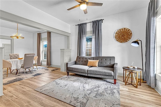 living room featuring ceiling fan with notable chandelier and light hardwood / wood-style floors