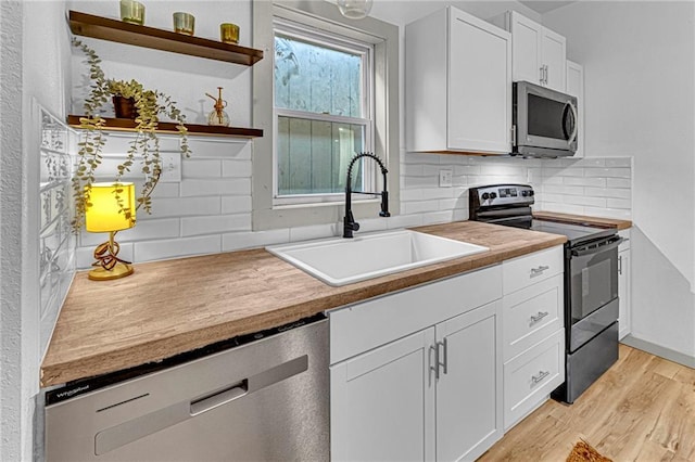 kitchen with stainless steel appliances, light hardwood / wood-style floors, sink, and white cabinets