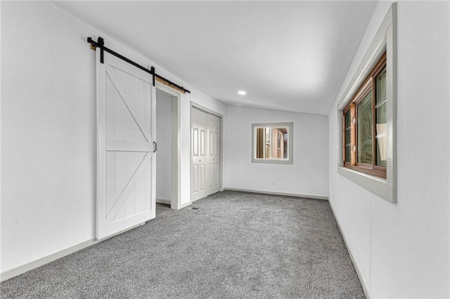 unfurnished bedroom featuring a barn door and carpet