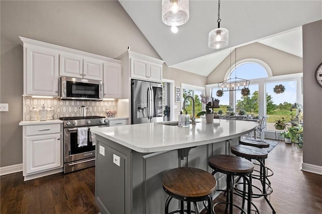 kitchen with pendant lighting, sink, appliances with stainless steel finishes, white cabinetry, and an island with sink