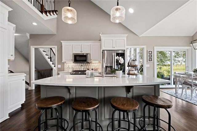 kitchen with a spacious island, stainless steel appliances, decorative light fixtures, and white cabinets