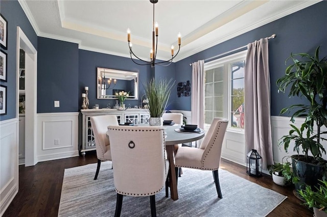 dining room featuring dark wood-type flooring, crown molding, a raised ceiling, and a notable chandelier