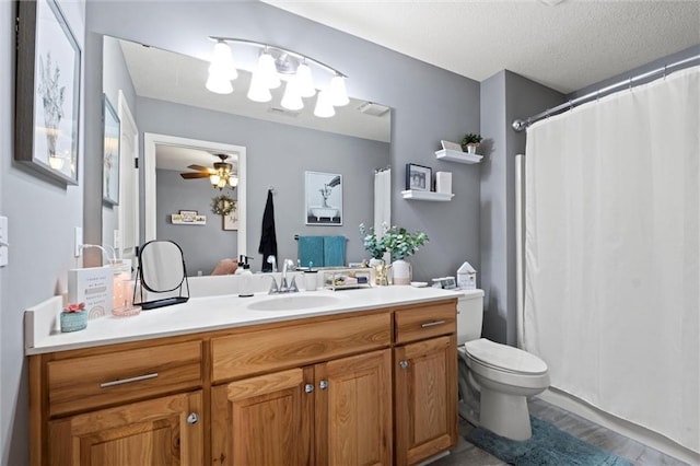 bathroom with ceiling fan, vanity, toilet, and a textured ceiling