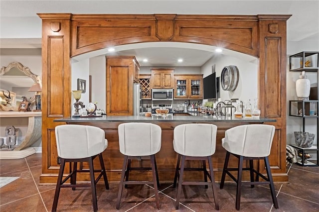 bar featuring stainless steel appliances, dark tile patterned flooring, and sink