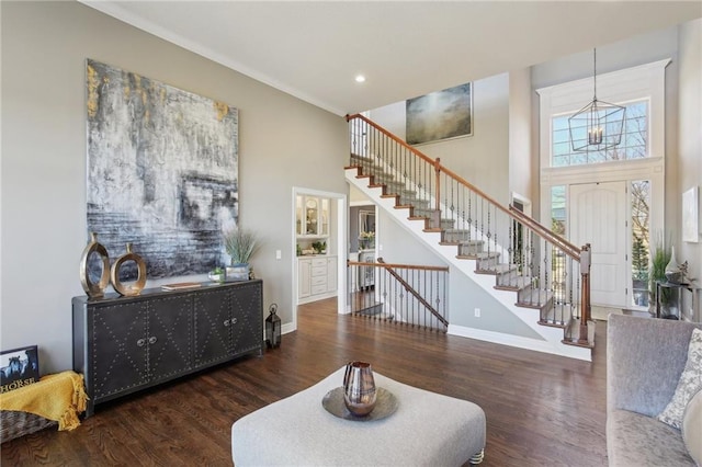 living area with baseboards, a towering ceiling, stairway, wood finished floors, and recessed lighting