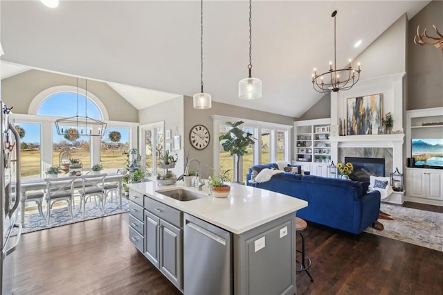 kitchen with a notable chandelier, stainless steel appliances, a sink, light countertops, and dark wood-style floors