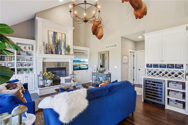 living room with beverage cooler, visible vents, a tiled fireplace, dark wood-style floors, and an inviting chandelier