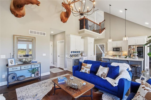 living area with beverage cooler, visible vents, baseboards, stairs, and dark wood finished floors