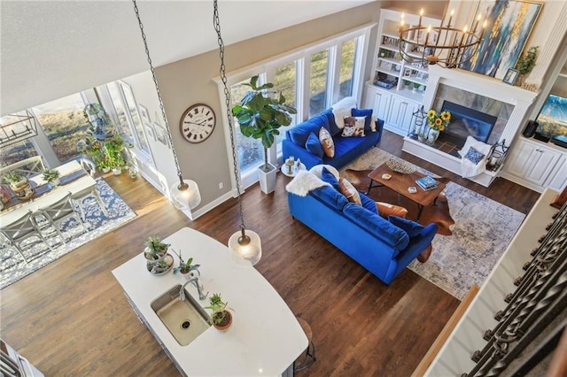 living room with a chandelier, a tile fireplace, wood finished floors, and baseboards