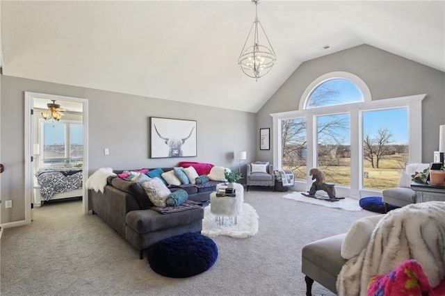 carpeted living area with high vaulted ceiling, plenty of natural light, and a notable chandelier