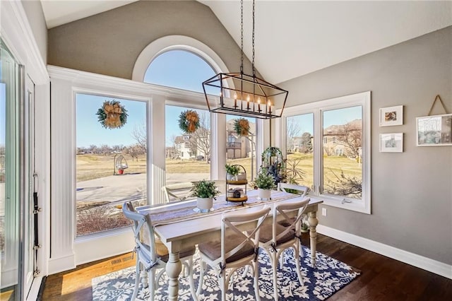 dining room with lofted ceiling, a notable chandelier, baseboards, and wood finished floors