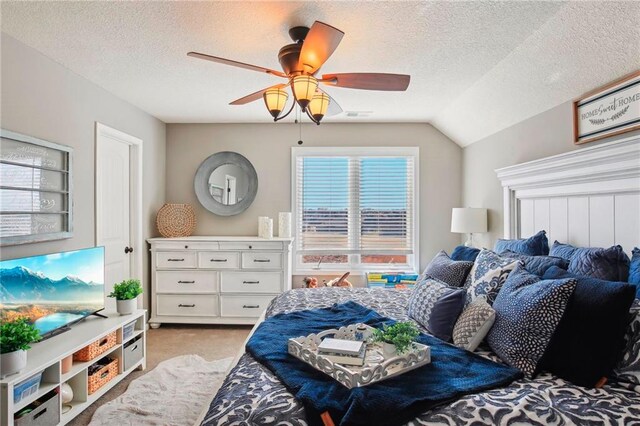 bedroom featuring ceiling fan, vaulted ceiling, a textured ceiling, and light colored carpet