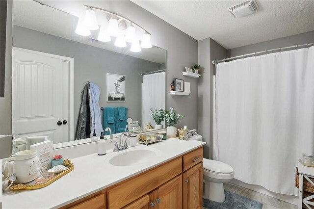 bathroom featuring visible vents, toilet, a textured ceiling, and vanity