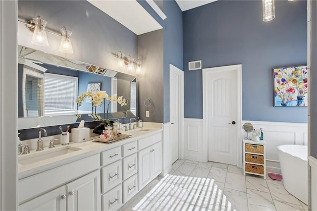 full bathroom featuring marble finish floor, visible vents, a sink, and wainscoting