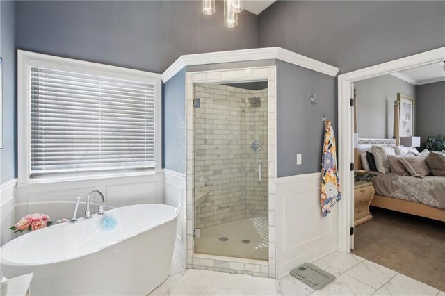 bathroom featuring marble finish floor, a wainscoted wall, a soaking tub, a decorative wall, and a stall shower