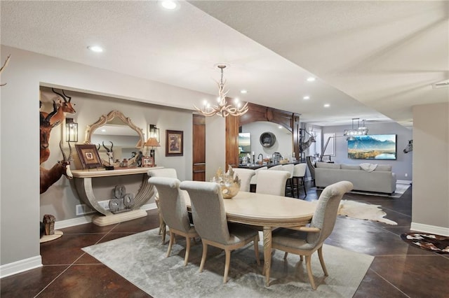 dining space with a textured ceiling, baseboards, a notable chandelier, and recessed lighting