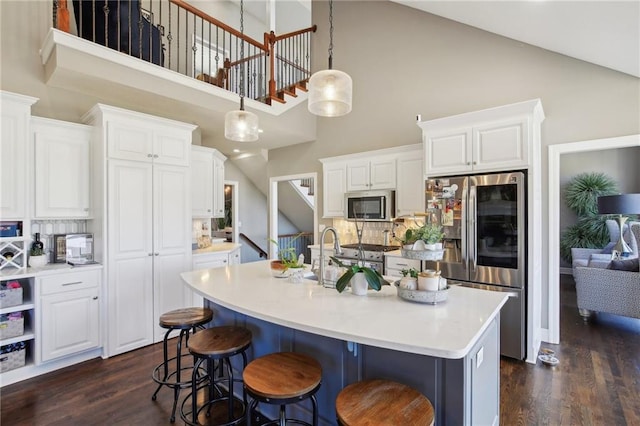 14110 Wingfoot Ct, Basehor, KS 66007 - kitchen featuring high vaulted ceiling, decorative backsplash, stainless steel appliances, white cabinetry, and dark wood-style flooring