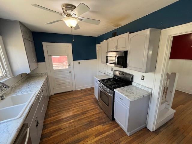 kitchen with ceiling fan, a sink, light countertops, appliances with stainless steel finishes, and dark wood finished floors