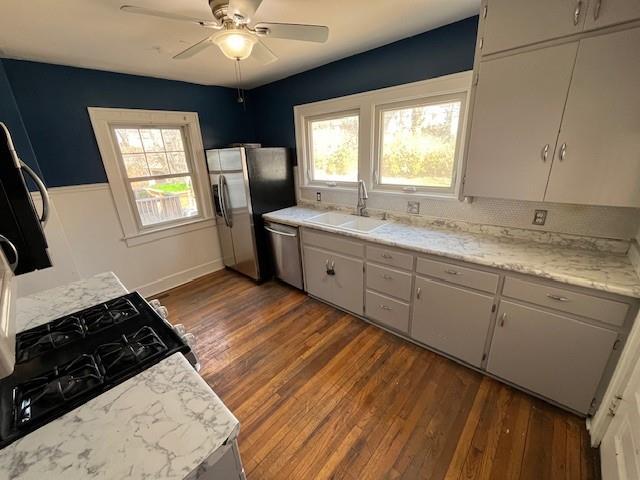 kitchen featuring white cabinets, a ceiling fan, dark wood finished floors, appliances with stainless steel finishes, and a sink