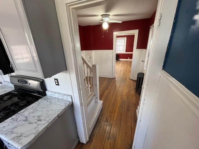 corridor featuring a wainscoted wall, an upstairs landing, and hardwood / wood-style flooring