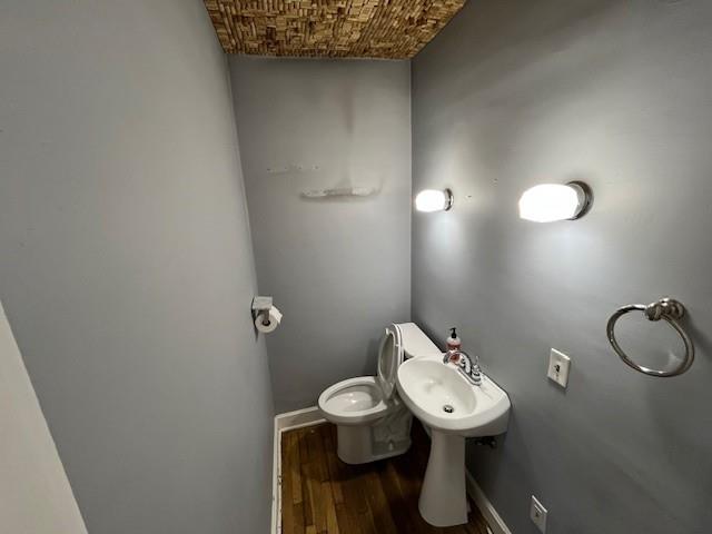 bathroom with wood finished floors, toilet, and baseboards