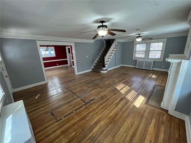 unfurnished living room featuring baseboards, stairway, radiator heating unit, wood-type flooring, and crown molding