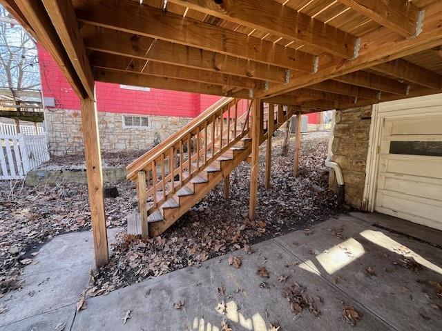 view of patio / terrace featuring a garage, stairway, and fence