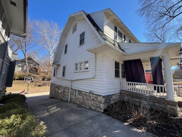 view of side of home with covered porch and a gambrel roof