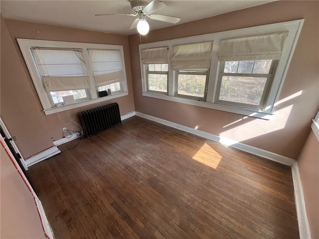 interior space with dark wood finished floors, baseboard heating, radiator heating unit, a ceiling fan, and baseboards