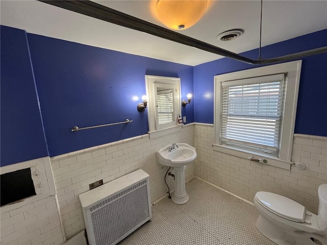 bathroom featuring visible vents, radiator, a wainscoted wall, tile patterned flooring, and tile walls