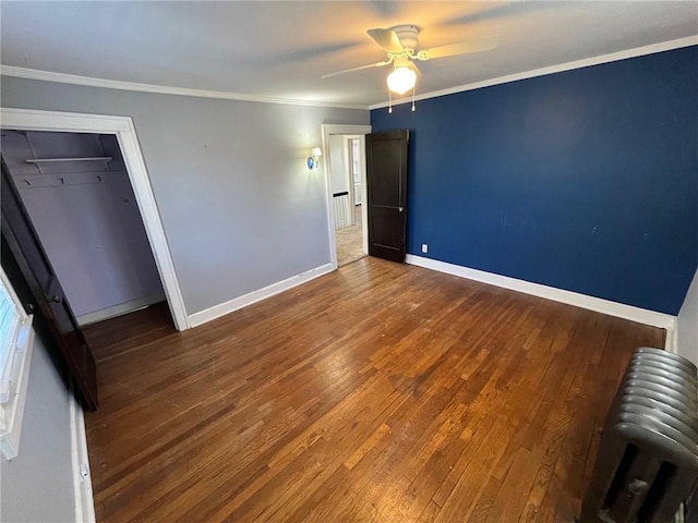 unfurnished bedroom featuring radiator heating unit, ornamental molding, a ceiling fan, wood finished floors, and baseboards