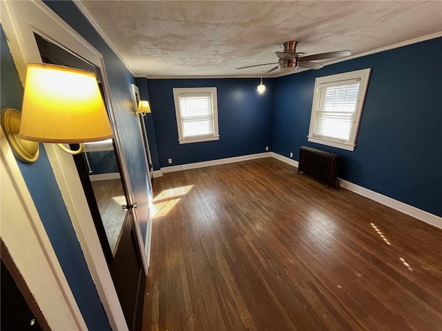 unfurnished bedroom featuring baseboards, a ceiling fan, radiator heating unit, ornamental molding, and wood finished floors