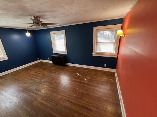 spare room with baseboards, radiator heating unit, ceiling fan, hardwood / wood-style floors, and crown molding