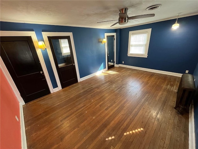 unfurnished bedroom featuring wood-type flooring, visible vents, ornamental molding, ceiling fan, and baseboards