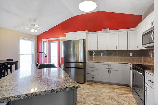 kitchen featuring lofted ceiling, visible vents, stainless steel appliances, and a sink