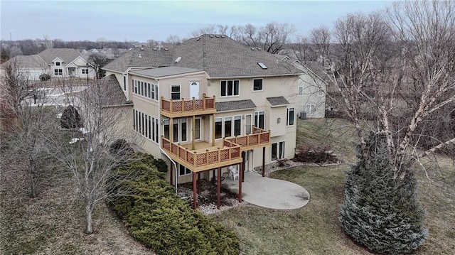 back of property featuring a wooden deck, a yard, and a patio