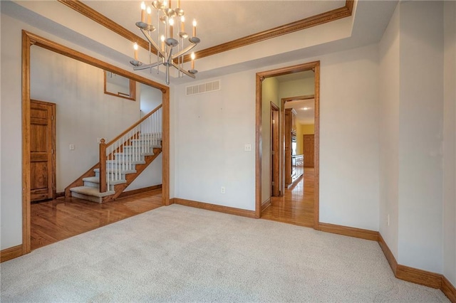 carpeted spare room with an inviting chandelier, crown molding, and a raised ceiling