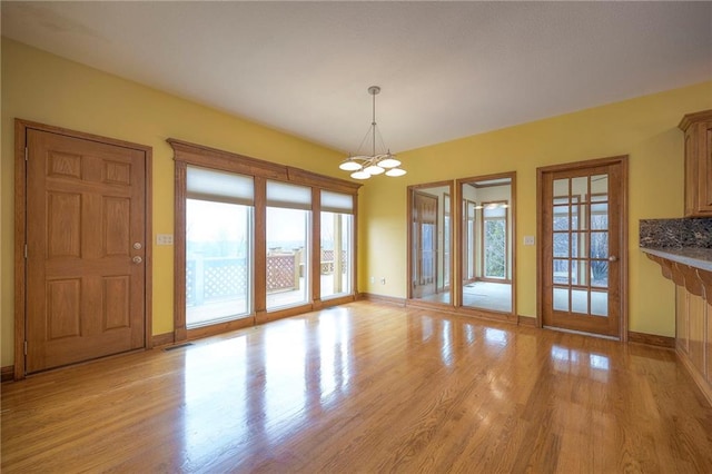 unfurnished dining area with an inviting chandelier and light hardwood / wood-style flooring